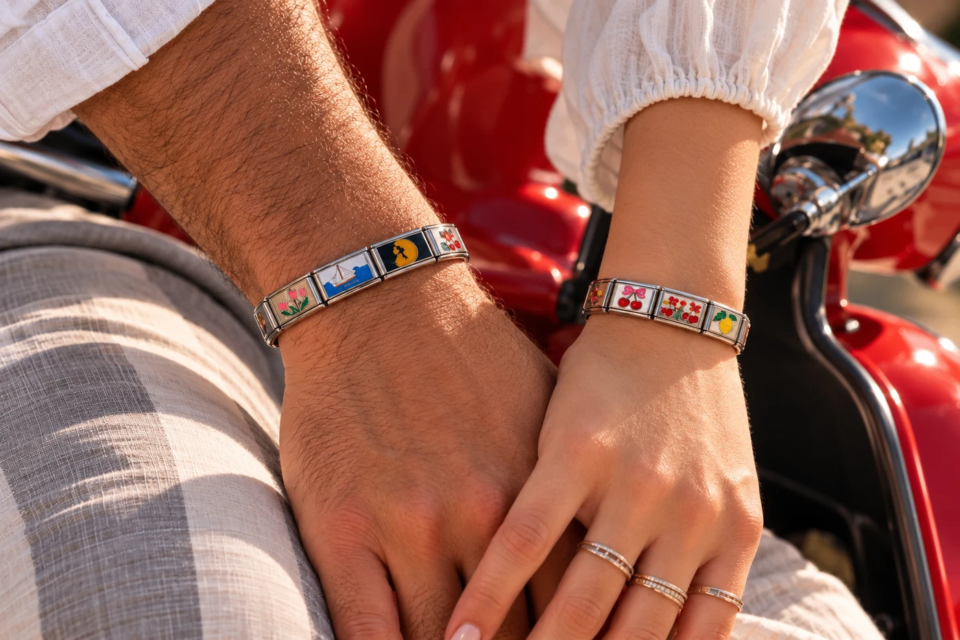 Two wrists wearing PEZZO charm bracelets beside a red Vespa